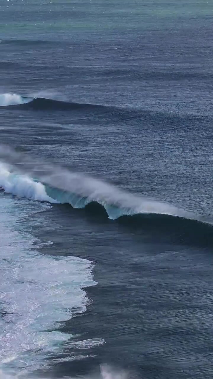 Powerful surf waves roll steadily under clear skies, showcasing nature's energy. Suitable for projects focusing on coastal environments or ocean dynamics.