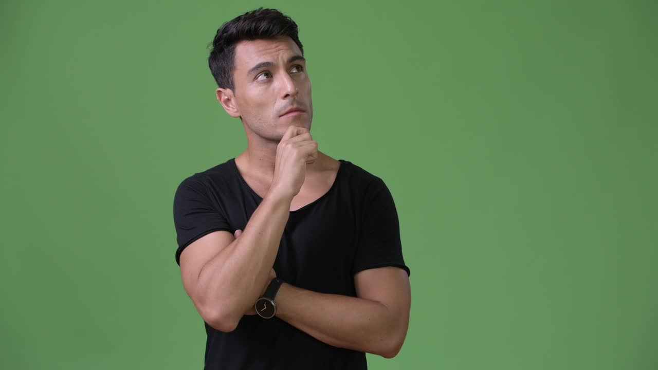 joven y guapo hombre hispano contra un fondo verde