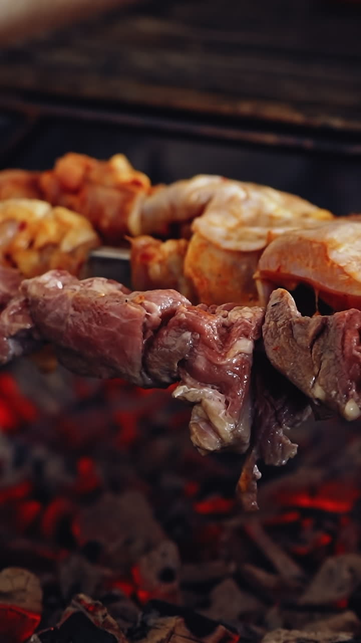 Meat cooking on charcoal. Delicious barbeque on metal skewers. Process of frying juicy meat. Close-up. Vertical video