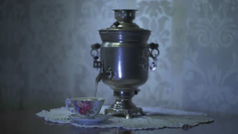 pouring hot water from a soviet vintage samovar electric metal tea kettle into a gorgeous cup