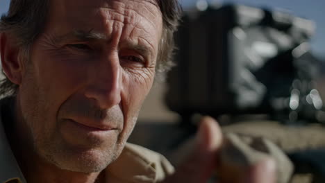 close-up of a man holding a rock or specimen outdoors