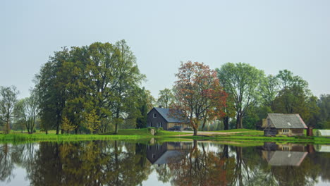 Weather-season-change-transition-summer-winter-of-house-on-lake-with-trees,-Latvia