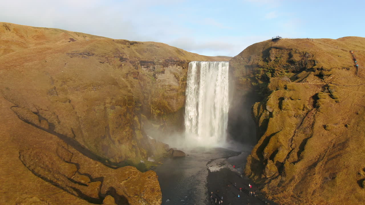 avión no tripulado cinematográfico cascada de skogafoss islandia panorámica a la izquierda con pájaros, arco iris y luz del sol de la tarde