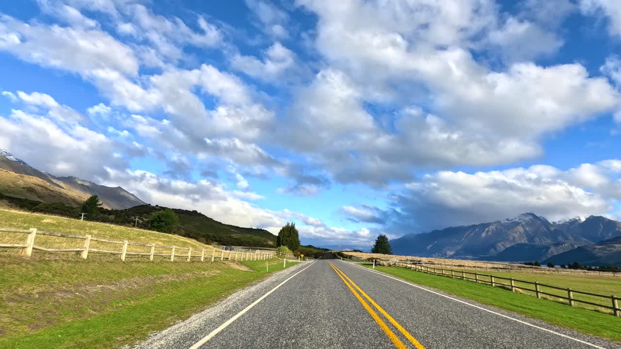 Forward-facing drive on rural road, bright daylight, mountain landscape, wide angle, smooth camera motion