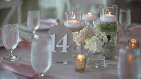 details-of-a-reception-table-setup,-featuring-elegant-tableware,-beautifully-lit-candles,-and-glistening-glassware