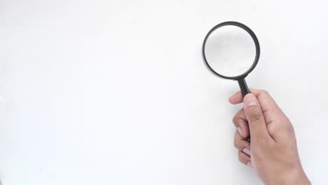 hand holding a magnifying glass on a white background