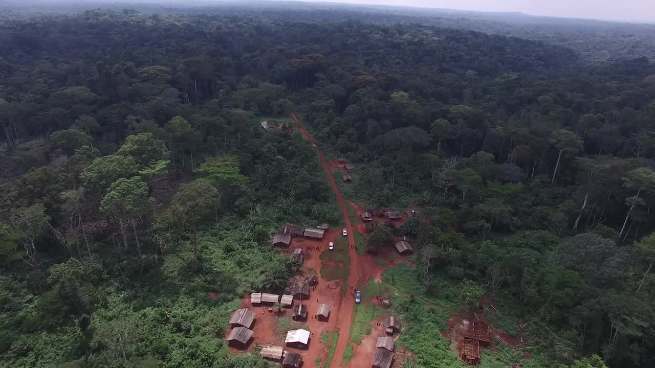 dron volando sobre un pueblo que parece enterrado en el bosque