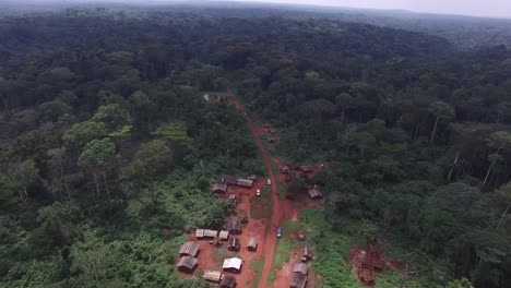 drone flying above a village as it appears buried in the forest