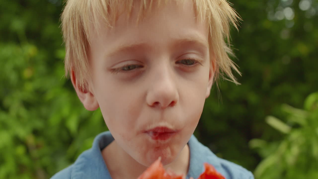 Adorable little boy eating a slice of fresh watermelon