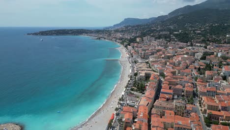 Blue-waters-of-Soleil-bay-at-town-of-Menton-in-French-riviera,-Aerial-flyover-shot
