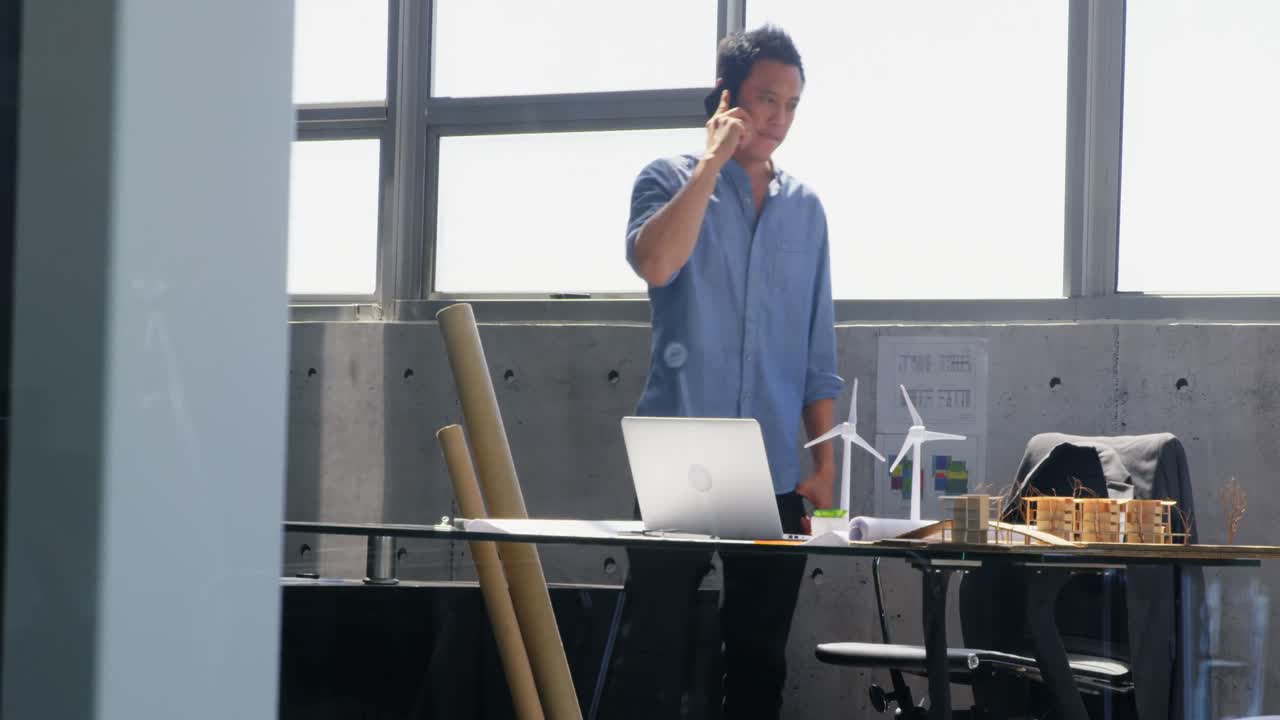 아시아 남성 건축가 가 현대적 인 사무실 4k 에서 휴대 전화 로 이야기 하는 전면 전망