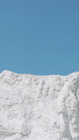 male athlete runs on a white mountain raising hands up. victory celebration. vertical video