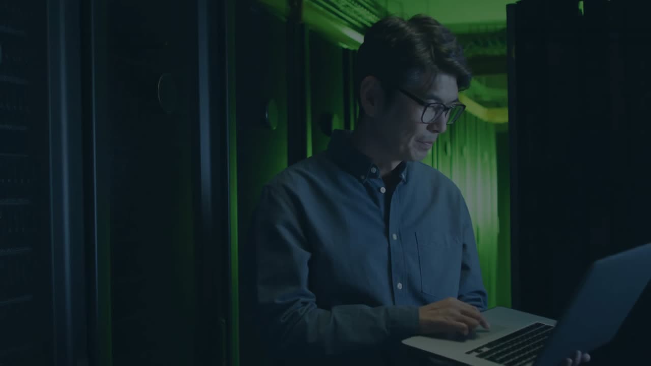 IT specialist typing on laptop in server room, glitch lines generating encryption overlays