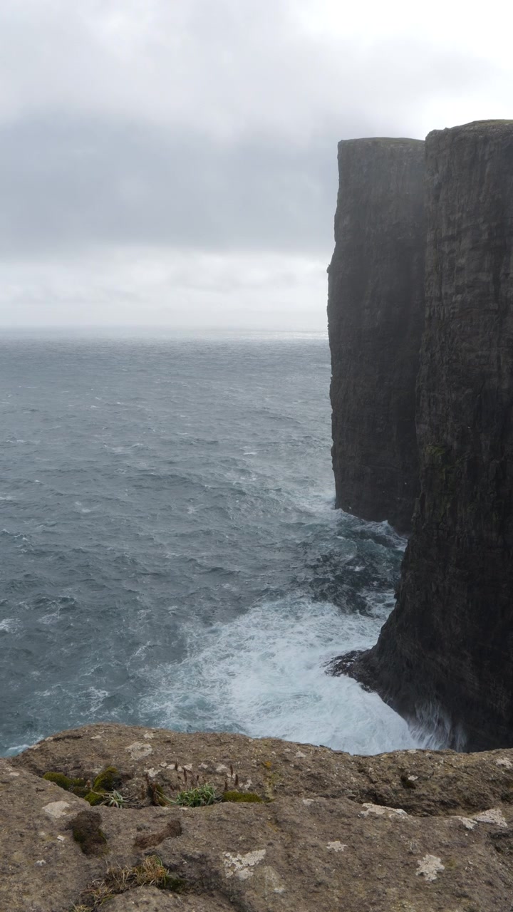 Vertical - Atlantic Ocean Waves Splashing On Feet of Black Cliffs Formation In Faroe Islands. slow motion