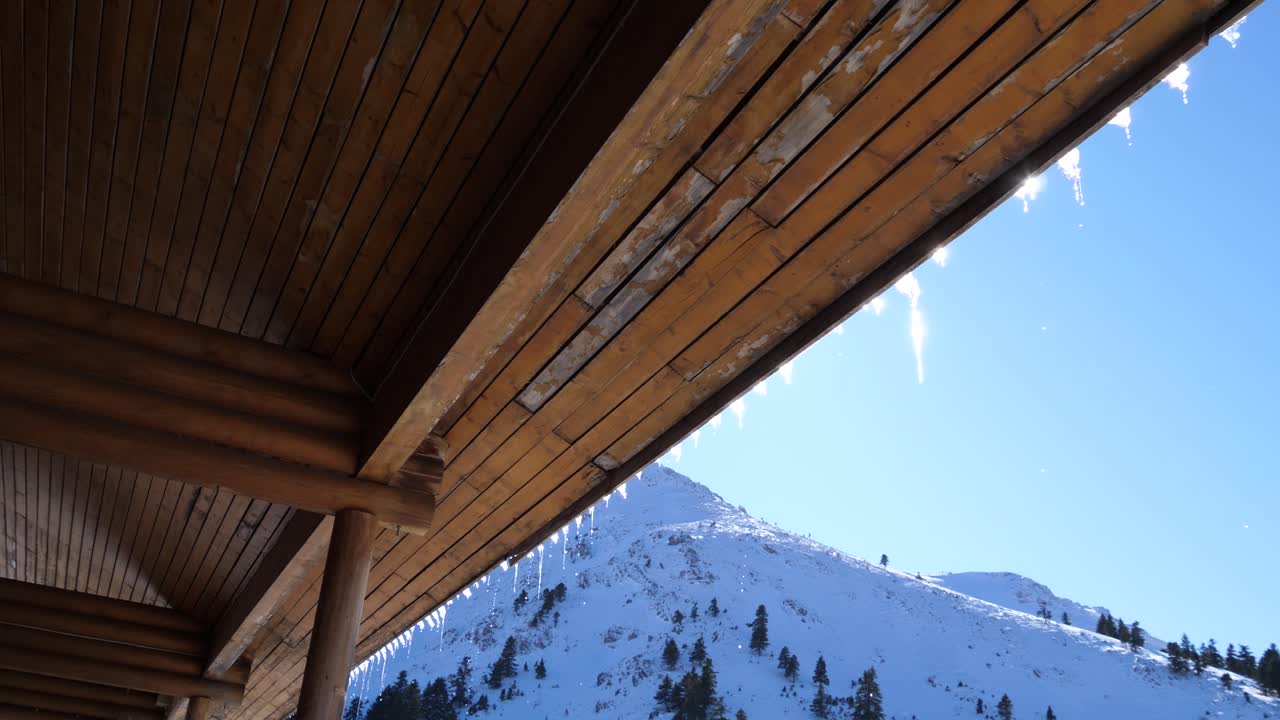 hielo derritiéndose del techo de madera de un chalet en un centro de esquí de montaña