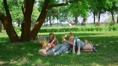 relaxed family lying on green grass on picnic. tranquil people rest in park.