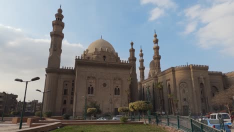 Exterior-view-of-Mosque-Madrasa-of-Sultan-Hassan-and-Al-Rifa'i-in-Cairo-with-car-traffic,-Egypt