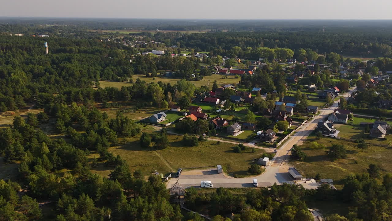 воздушный обратный подъем, раскрывающий прибрежные дома для отдыха и приморскую недвижимость в солнечном, европейском, серфинг-городе павилоста, латвия.