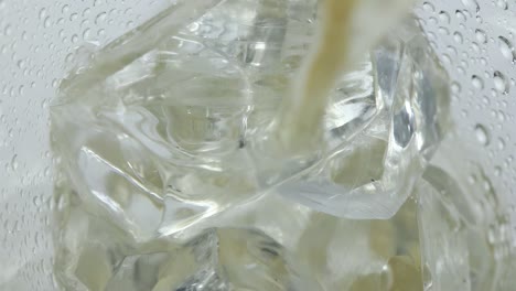 epic close-up in slowmotion, pouring a sparkling soda drink on ice cubes