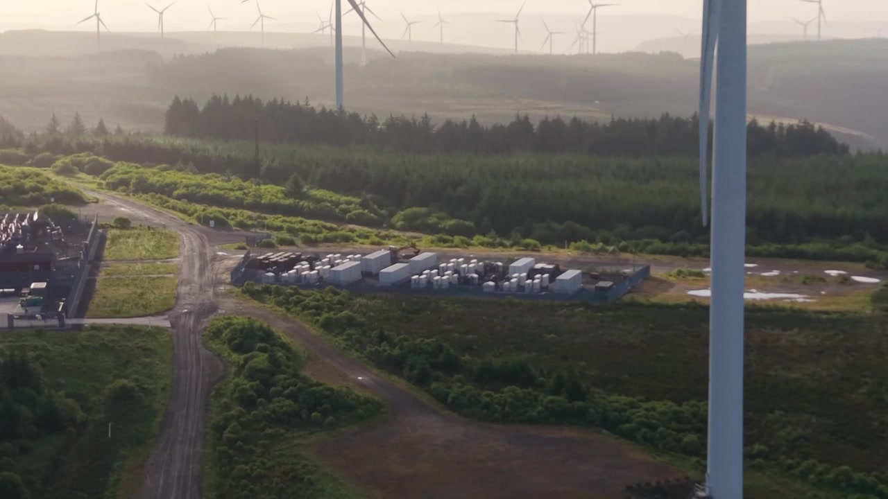 Descending Aerial of BESS Battery Energy Storage System on Wind Farm at Sunrise.