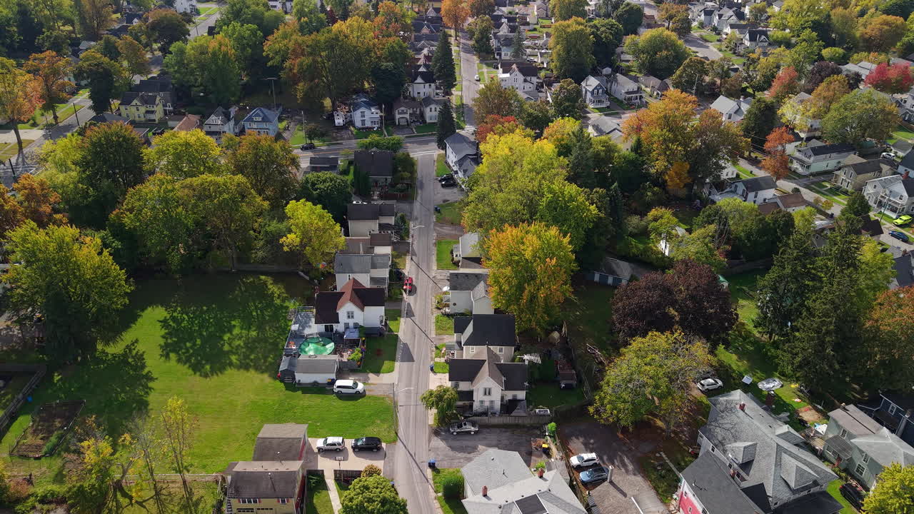 Vista aérea de um bairro residencial suburbano nos EUA com casas isoladas, jardins verdes e árvores de outono coloridas em um dia ensolarado