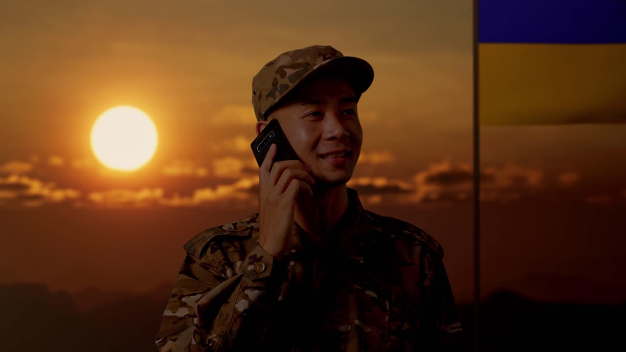 배경 에 우크라이나 국기 와 함께 해 가 지는 동안 전화 로 이야기 하는 군인