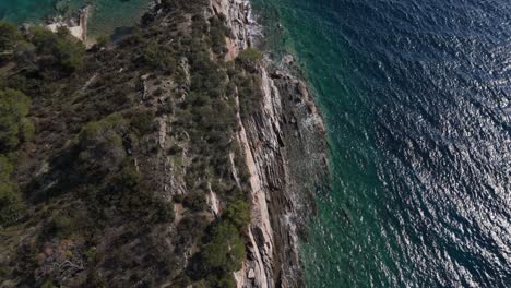 Vista-Aérea-De-Un-Acantilado-Que-Cae-Al-Mar-Con-Increíble-Agua-De-Mar-Clara-Golpeando-Las-Rocas