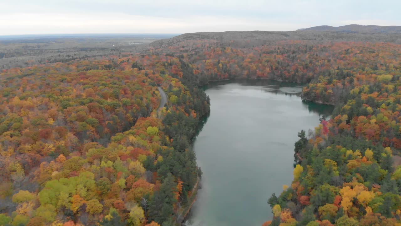 imágenes aéreas invertidas sobre el lago rosa en gatineau quebec con montañas y el agua azul en la distancia y miradores y colinas con bosques otoñales a ambos lados