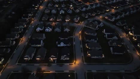 Toma-Aérea-Nocturna-De-Un-Barrio-Residencial-Con-Calles-Y-Casas-Iluminadas