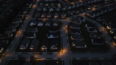 nighttime aerial shot of a residential neighborhood with lit streets and houses