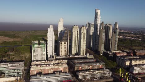 aerial drone flight towards skyline of puerto madero area in buenos aires in front of river at sunset