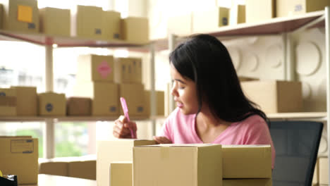 asian women business owner working at home with packing box on workplace