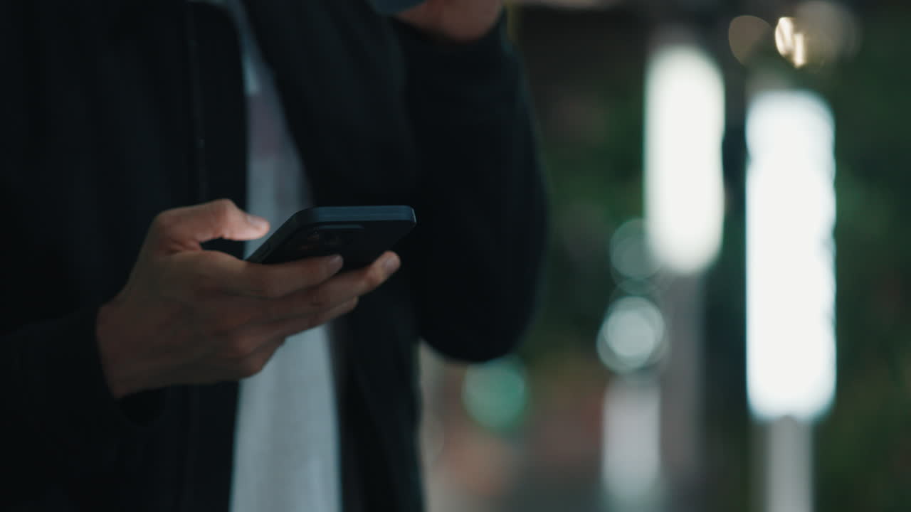 Person using phone while drinking coffee outdoors at night