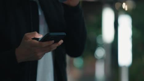 person using phone while drinking coffee outdoors at night