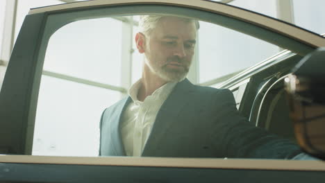 man inspecting a car in a showroom