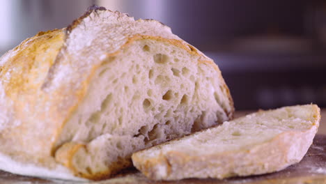 Pan-De-Masa-Fermentada-Recién-Horneado-Cortado-En-Una-Tabla-De-Madera---Primer-Plano,-Toma-Deslizante-A-La-Izquierda