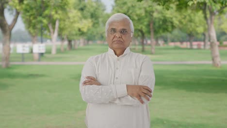 Confident-Indian-old-man-standing-crossed-hands-in-park