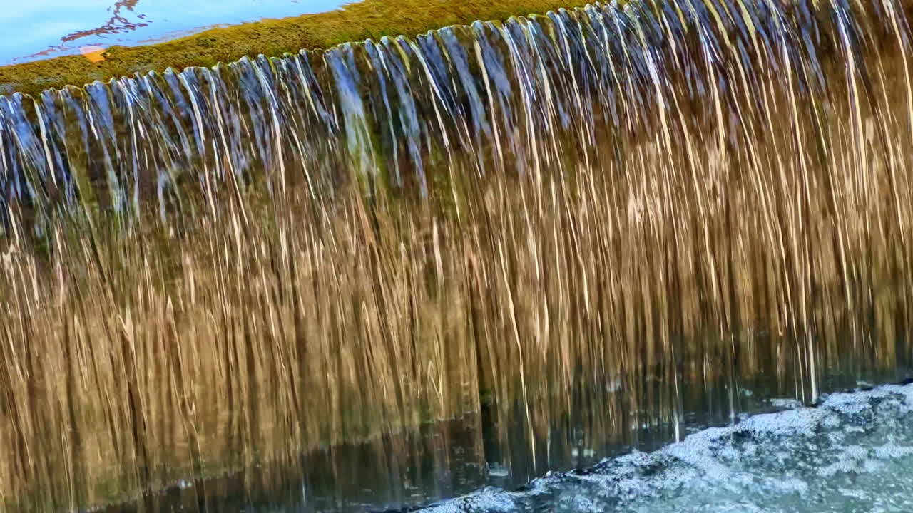Wasser kaskadiert sanft über moosbewachsene Felsen in einer ruhigen Umgebung an einem sonnigen Nachmittag in einer malerischen Naturlandschaft