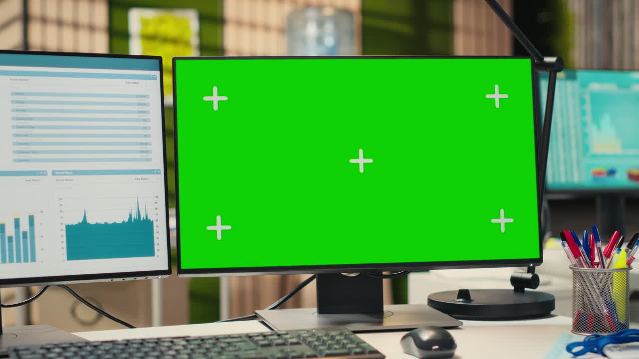 Empty modern office space presents dual monitors and green screen on display