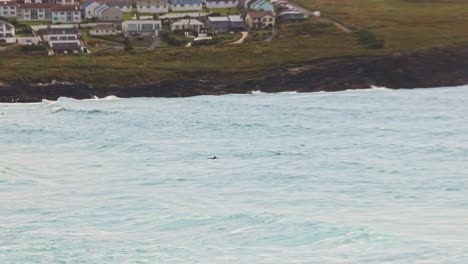 hand-held tracking shot of a surfer heading out into fistral beach to catch waves