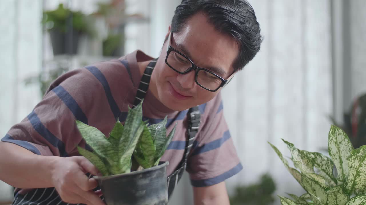 손에 든 식물과 머리를 흔들고 있는 아시아 남자의 근접 사진