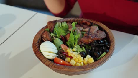 Vista-De-Arriba-Hacia-Abajo-De-Una-Mujer-Comiendo-Ensalada-De-Cerdo-A-La-Parrilla-De-Un-Tazón-De-Madera