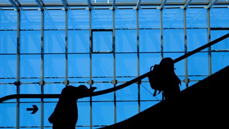la escalera del aeropuerto de la ventana de vidrio con silueta en movimiento de personas