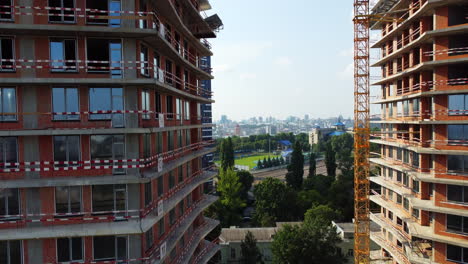 Drone-rising-in-front-of-two-buildings-under-construction-in-city-center-to-reveal-beautiful-cityscape-of-Kyiv,-Ukraine