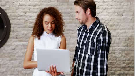 male and female executives discussing over laptop