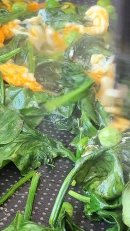 cooking scrambled eggs with spinach and peas