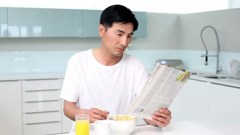 Hombre-Atractivo-Comiendo-Cereal-Y-Leyendo-Una-Revista