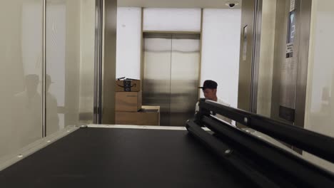 hombre moviendo casos de vuelo y cajas fuera del ascensor para un evento de transmisión en vivo