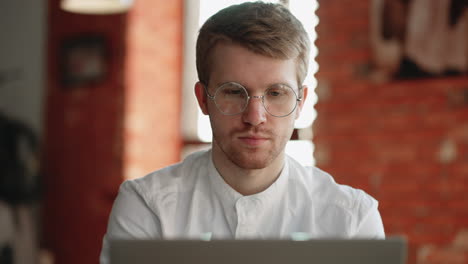 young it specialist is working with laptop remotely sitting in cafe or cozy coworking space portrait