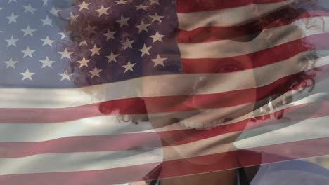 Animation-of-American-flag-waving-over-happy-mixed-race-woman-on-beach-by-seaside